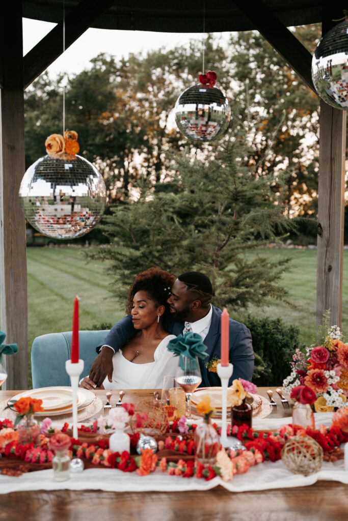 Disco balls and vibrant color sweetheart table at wedding reception
